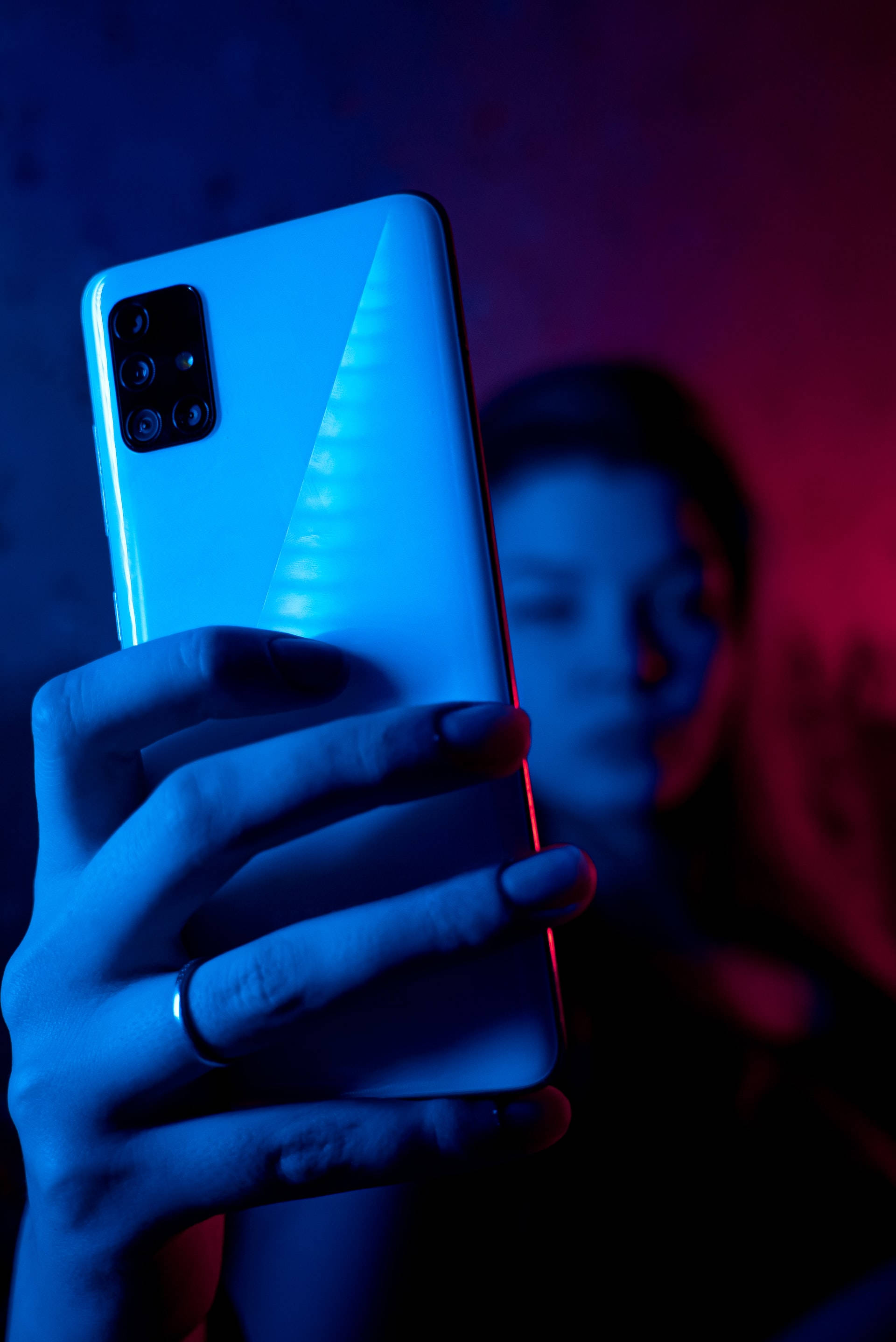 手持手机的女子蓝色霓虹 iPhone 壁纸