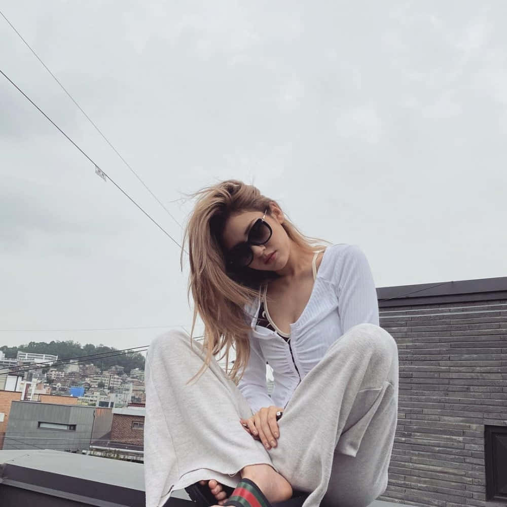一位戴着太阳镜坐在屋顶上的女性 壁纸