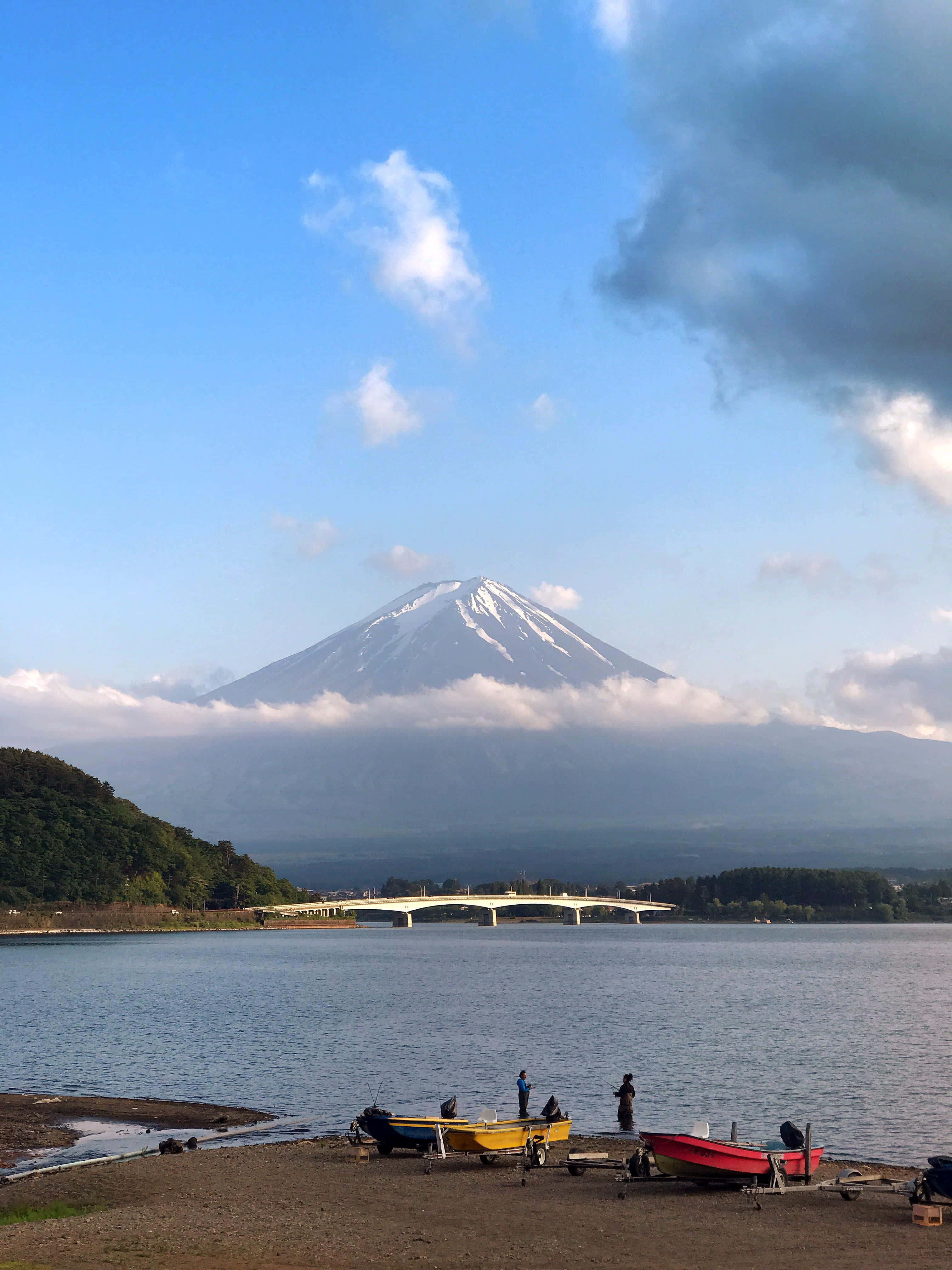 一群人坐在岸边，背景是一座山 壁纸