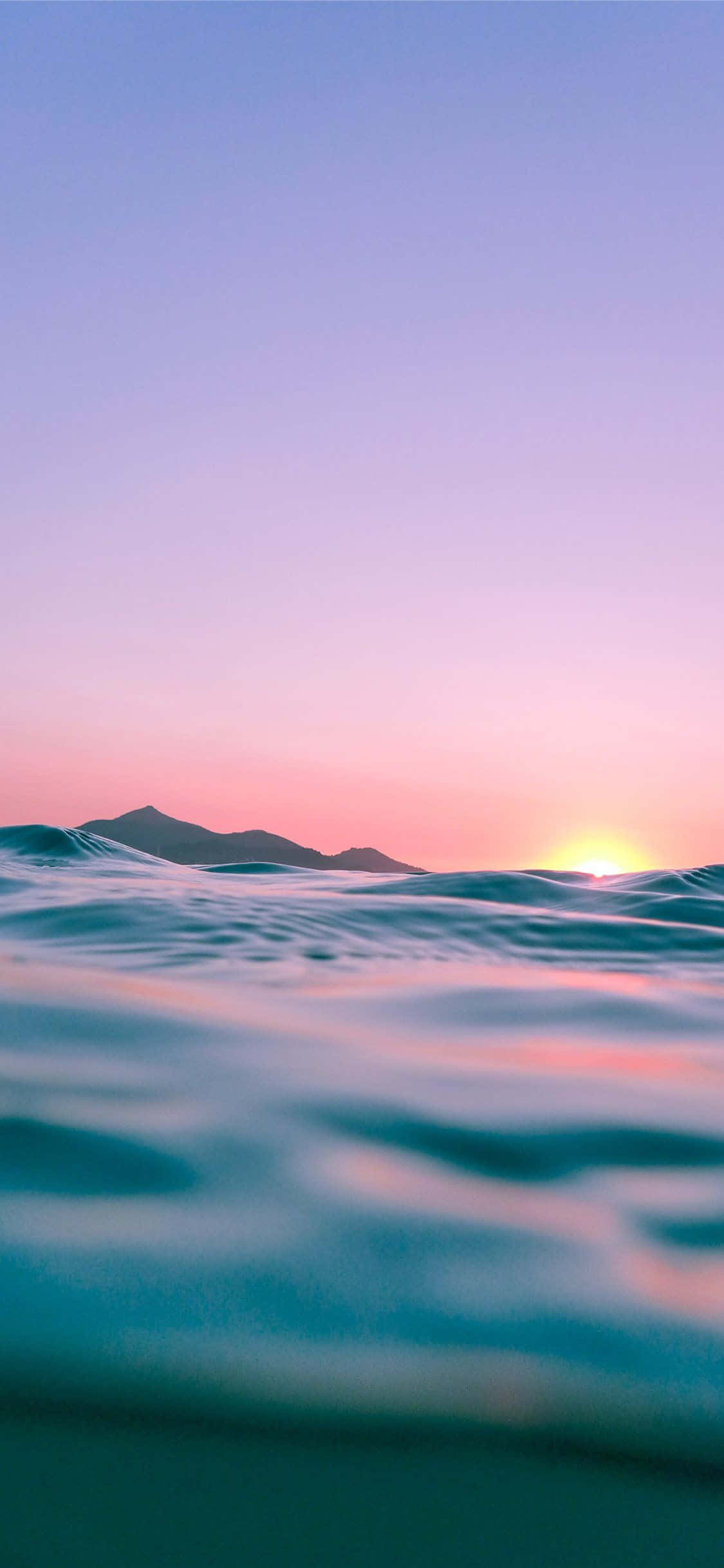 日落时分的海洋，海浪与山脉 壁纸