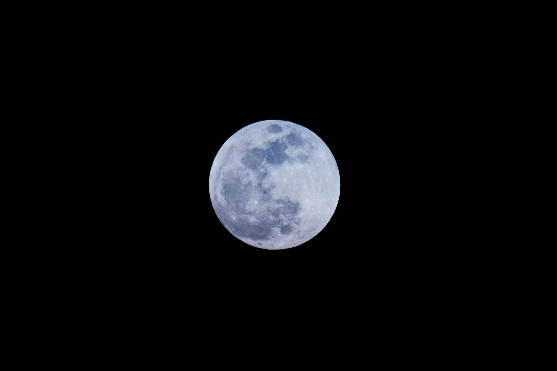 满月在午夜夜空中明亮照耀。月球表面可见陨石坑。