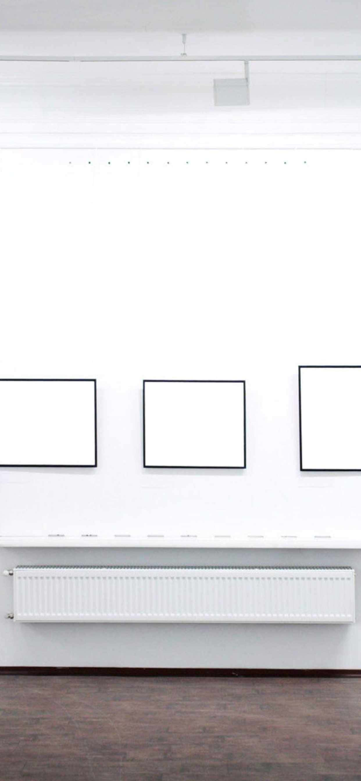一间白色房间，墙上挂着几幅空白画框 壁纸