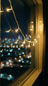 窗前仙女灯与夜间城市散景 — 圣诞美学 壁纸
