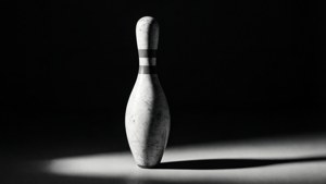 一个单独摆放的保龄球瓶，在戏剧性的灯光下呈现高对比黑白效果。