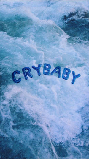 酷炫蓝色美学壁纸，巨大的气球字母“Crybaby”漂浮在蓝色海洋上。