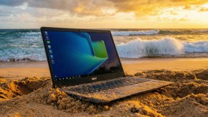 一台Chromebook在壮丽日落时静置于沙滩上。