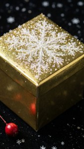 黑色表面上的闪亮金色礼物，雪花点缀，带有浆果。 — iPhone 7 壁纸