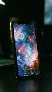 iPhone 17屏幕在黑暗中发光，显示银河壁纸。