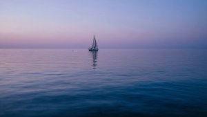 一艘孤帆在黄昏平静的海面上航行。 — 海洋 壁纸